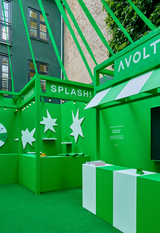AVOLT green exhibition booth with SPLASH! sign, star graphics, display counters and striped pedestal