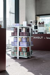 Retail packaging for AVOLT Square chargers on metal shelving at a café pop-up beside branded coffee bar